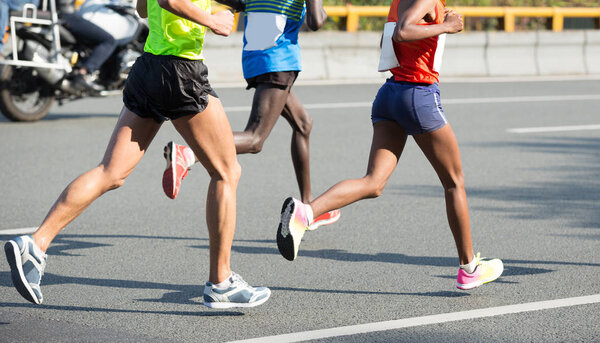 legs of marathon runners running on city road