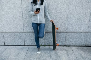 Bayan kaykaycı City duvara yaslanmış iken Smartphone kullanarak