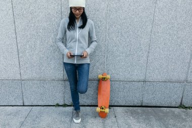 Bayan kaykaycı City duvara yaslanmış iken Smartphone kullanarak