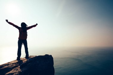 Sırt çantası ayakta gündoğumu rüzgarlı kenarı ile kadın hiker silüeti