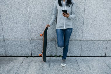 Bayan kaykaycı City duvara yaslanmış iken Smartphone kullanarak