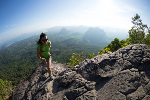 Young woman with backpacker climbing to mountain top