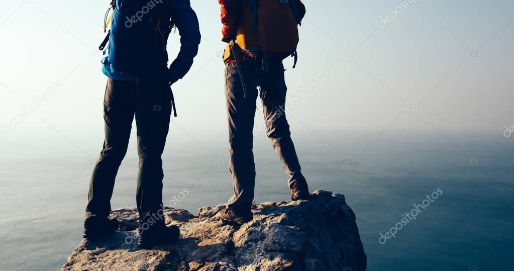two women hikers looking at seaside mountain top 