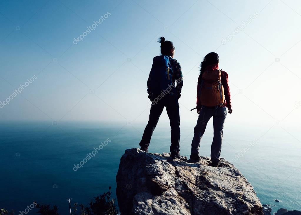 two women hikers looking at seaside mountain top 