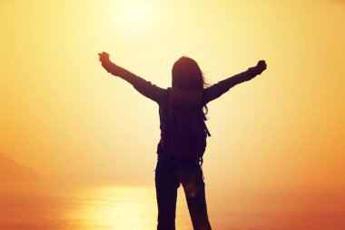 Sırt çantası ayakta gündoğumu rüzgarlı kenarı ile kadın hiker silüeti