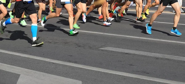 legs of marathon runners running on city road