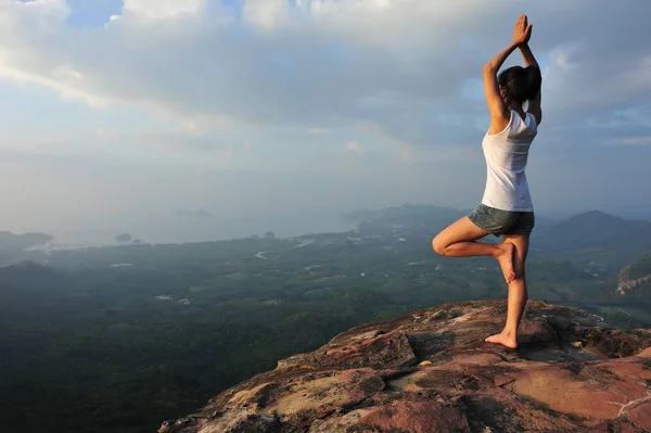 one woman practicing yoga at mountain peak