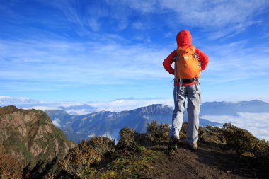 Dağ tepe üzerinde duran genç kadın backpacker 