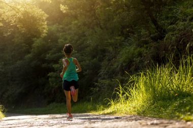 Young fitness woman athlete running on forest trail