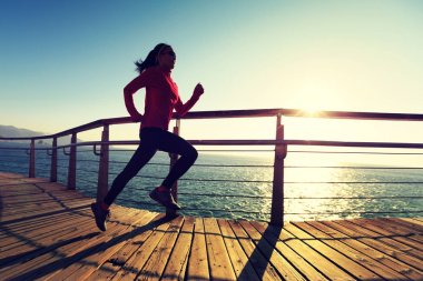 Sahil sahil üzerinde gündoğumu sırasında çalışan sportif genç kadın