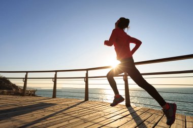 Sahil sahil üzerinde gündoğumu sırasında çalışan sportif genç kadın