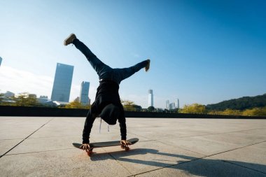 female skateboarder doing a handstand on skateboard in city clipart