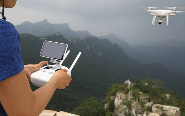 Woman controlling flying drone which taking photo of the great wall landscape in China