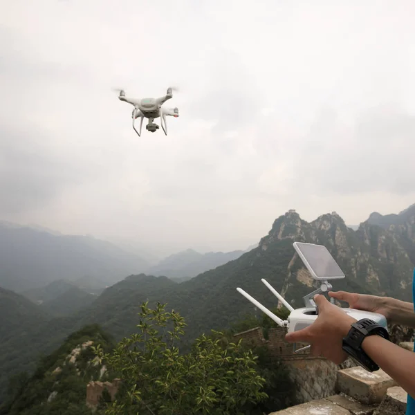 Woman controlling flying drone which taking photo of the great wall landscape in China