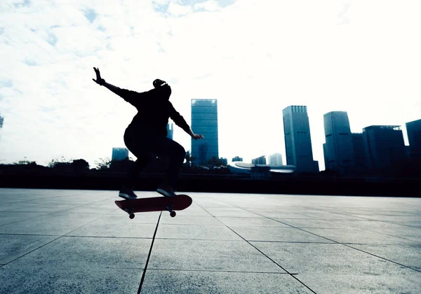 Skateboarder doing a trick named ollie in city park with skateboard