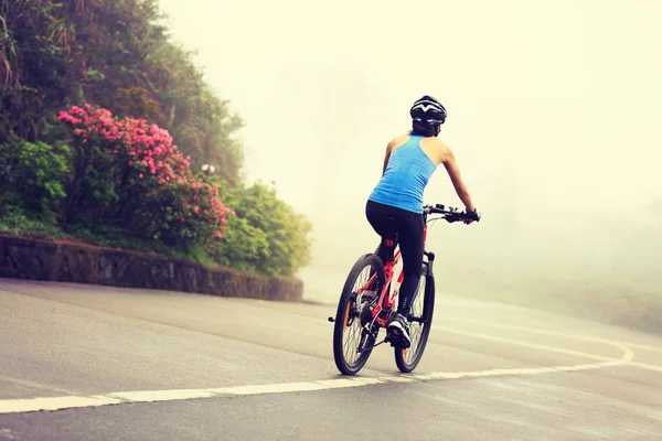 Young woman cyclist riding mountain bike on trail