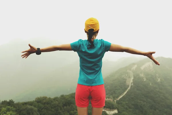 成功的女子徒步旅行者张开双臂到山顶上的长城 — 图库照片