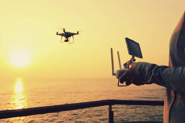 silhouette of remote control a flying drone which taking photo over sunrise sea
