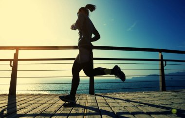 Sahil sahil gündoğumu sırasında sportif kadın koşucu sabah egzersiz
