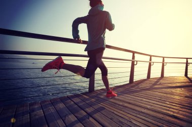 Güneş doğarken sahil kenarında koşan sportif fitness kadın koşucusu