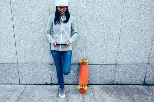 Skateboarder Femminile Utilizzando Smartphone Mentre Appoggiato Muro Città — Foto Stock