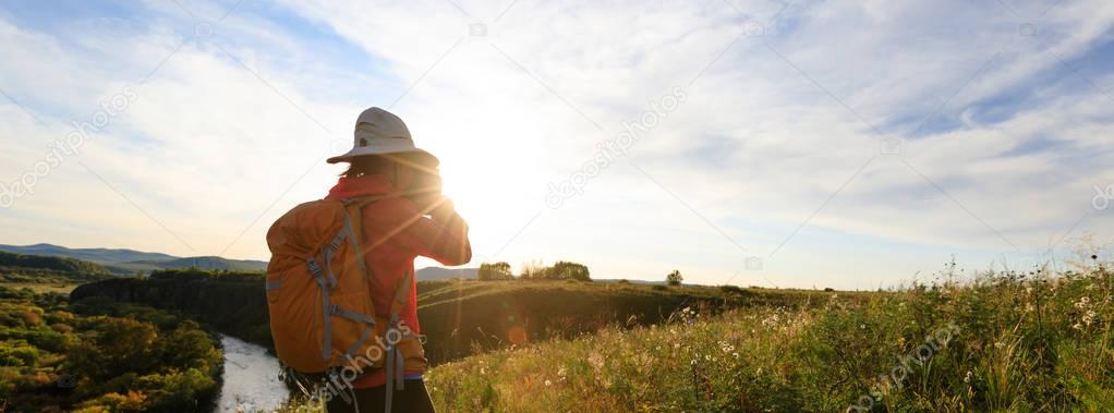 young woman photographer taking photo on sunset mountain top