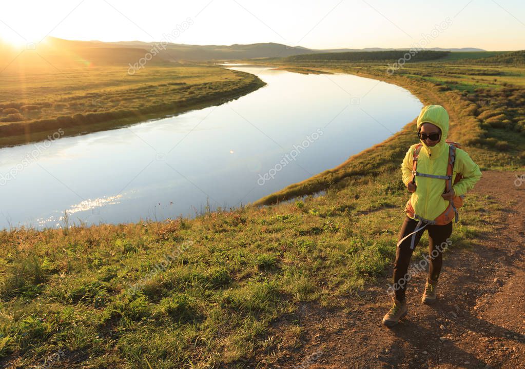 Young woman hiking on sunset  riverside hill