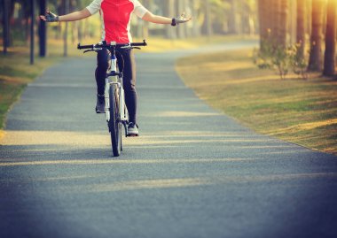 kadın bisikletçi binicilik bisiklet tropikal Park uzanmış kollarıyla