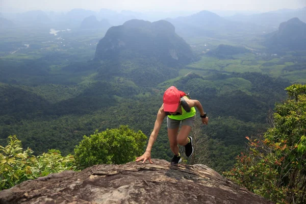 Young fitness woman running up to the mountain top