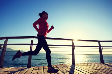 Sportif kadın jogger sahil sahil üzerinde gündoğumu sırasında çalışan