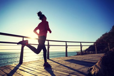 Sportif kadın jogger sahil sahil üzerinde gündoğumu sırasında çalışan