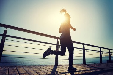 Sahil sahil üzerinde gündoğumu sırasında çalışan sportif kadın runner