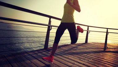 Sahil sahil üzerinde gündoğumu sırasında çalışan sportif kadın runner