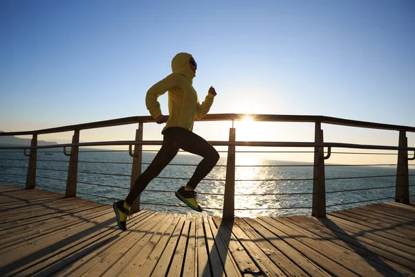 sporty female jogger morning exercise on seaside boardwalk during sunrise