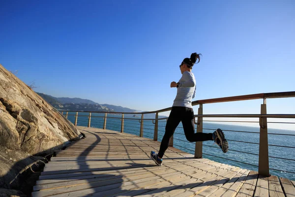 运动的女性慢跑在海滨木板路上 — 图库照片