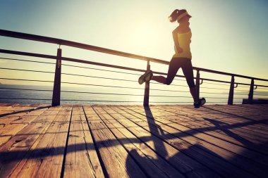 Güneş doğarken sahil kenarında koşan sportif fitness kadın koşucusu