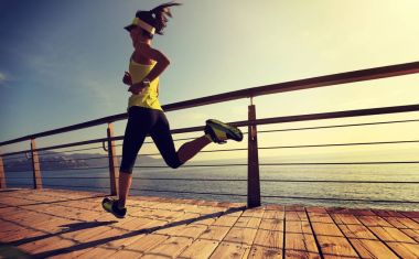 Güneş doğarken sahil kenarında koşan sportif fitness kadın koşucusu