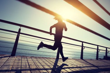 Sahil sahil üzerinde gündoğumu sırasında çalışan sportif kadın runner