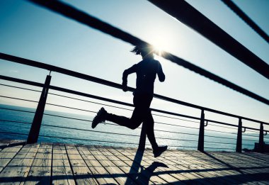 Güneş doğarken sahil kenarında koşan sportif fitness kadın koşucusu