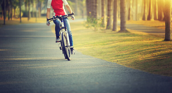 woman cyclist riding bike in tropical park