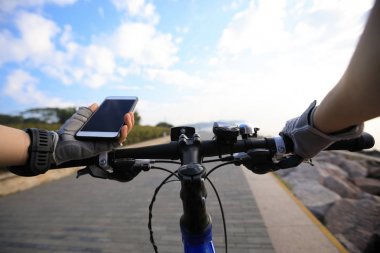 Smartphone navigasyon için dağ bisikleti sahil yolu üzerinde sürme kullanarak bisikletçi