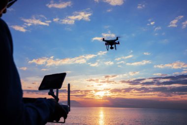 Kadın silueti uzaktan kumandayla uçan robot hangi alarak fotoğraf gündoğumu deniz üzerinde 