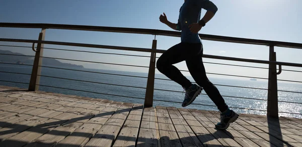 在日出时在海滨木板上奔跑的运动的少妇 — 图库照片