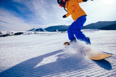 Bir snowboardcu kış dağlarında snowboard yapıyor.