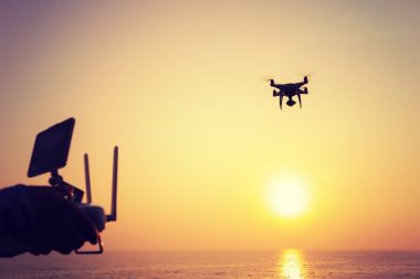 Uzaktan denetim uçan bir tutan kadın silüeti robot hangi alarak fotoğraf gündoğumu deniz üzerinde