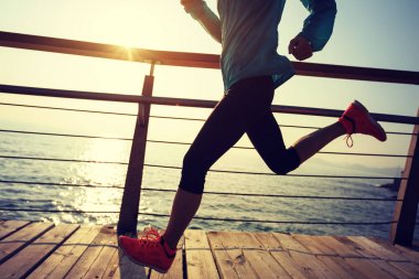 Güneş doğarken sahil kenarında koşan sportif fitness kadın koşucusu