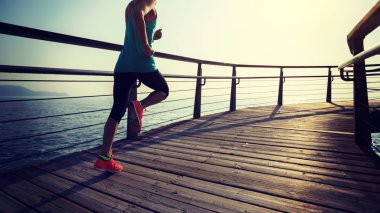 Güneş doğarken sahil kenarında koşan sportif fitness kadın koşucusu