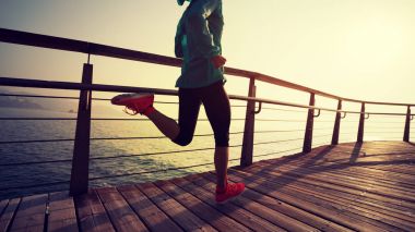 Güneş doğarken sahil kenarında koşan sportif fitness kadın koşucusu