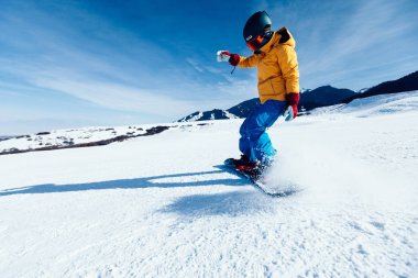 Bir snowboardcu kış dağlarında snowboard yapıyor.
