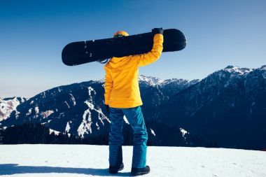 Kış zirvesinde snowboard yapan bir snowboardcu.
